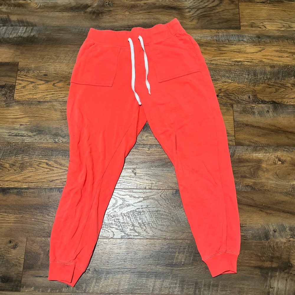 Bundle of 3 sweatpants. 2 black, 1 pink-orange.
